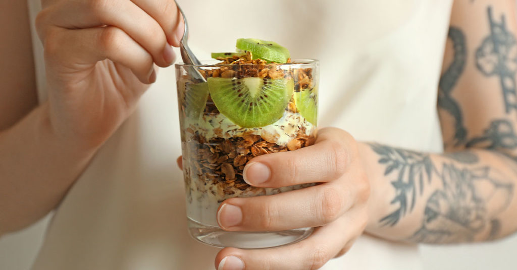 Imagen mujer sosteniendo vaso con fruta y granola